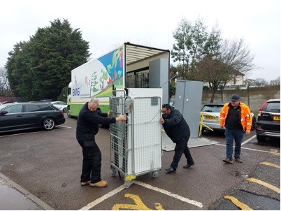 Business Moves Group employees unload office furniture from a truck in a car park