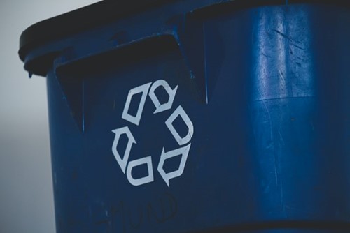 A blue waste bin with the recycling logo on it
