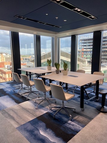 A conference room tables and chairs, and floor to ceiling windows with a view over Glasgow