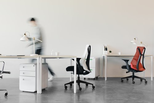 Desks and chairs in an office with an employee in the background